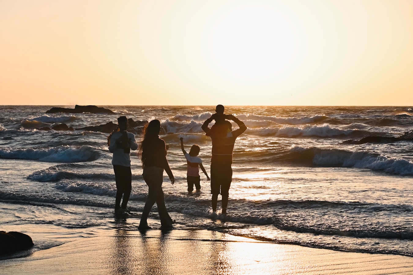 A family with three kids playing in the waves at sunset on a Costa Rica beach