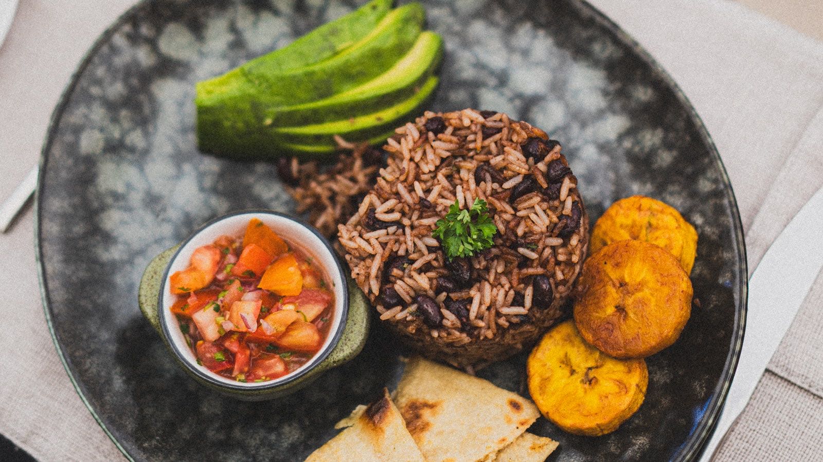 Costa Rican gallo pinto plate with rice, black beans, avocado, plantain, and fresh salsa